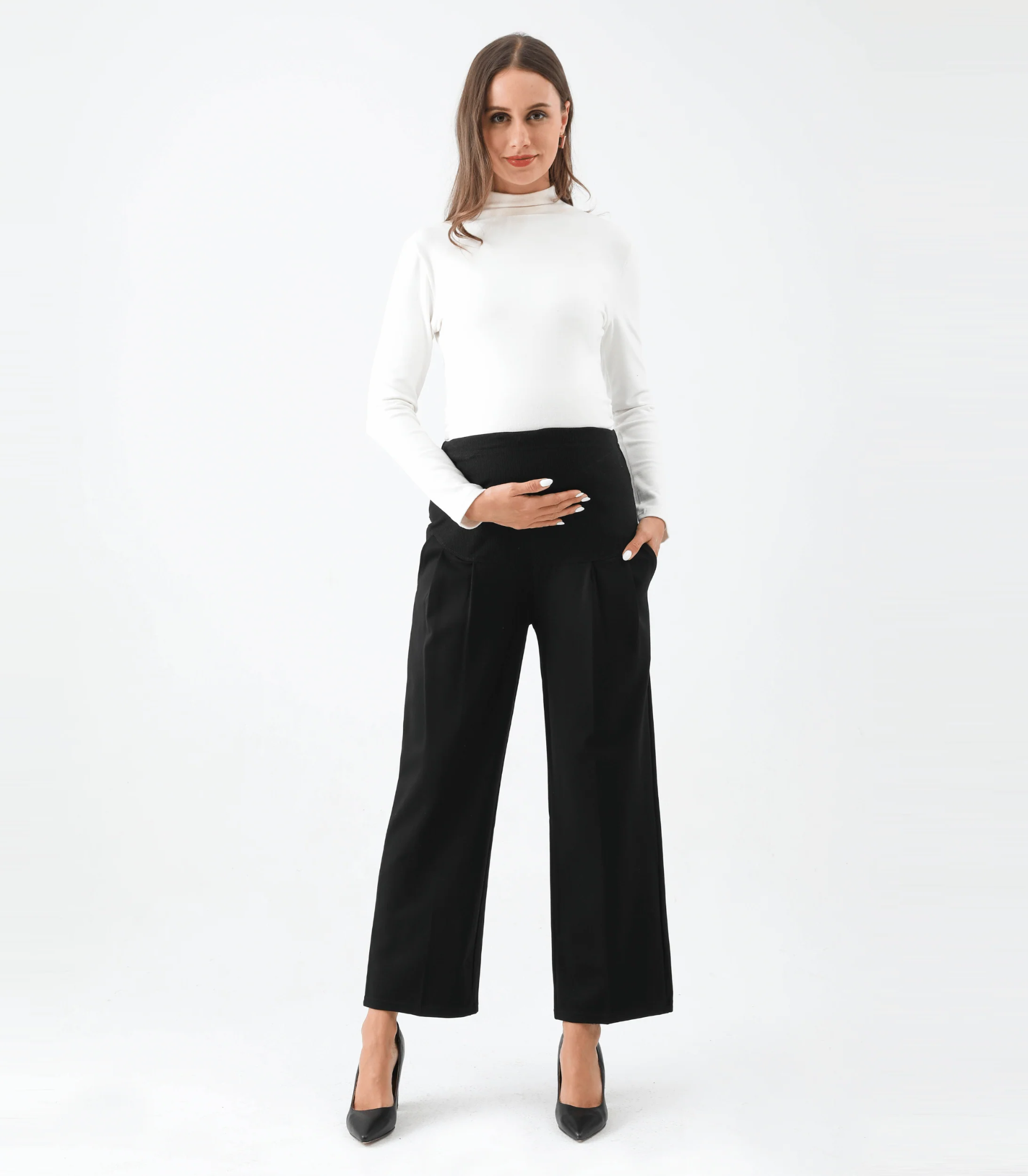 Woman in white top and black maternity pants posing.